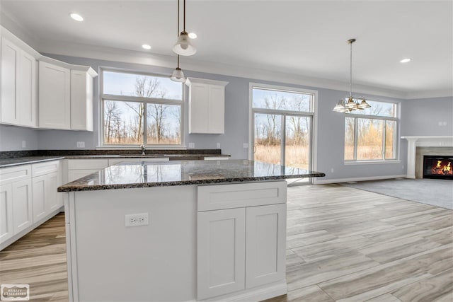 kitchen featuring pendant lighting, a kitchen island, white cabinets, and a chandelier