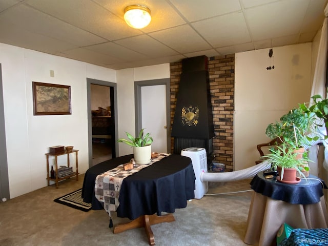 carpeted bedroom featuring brick wall and a drop ceiling