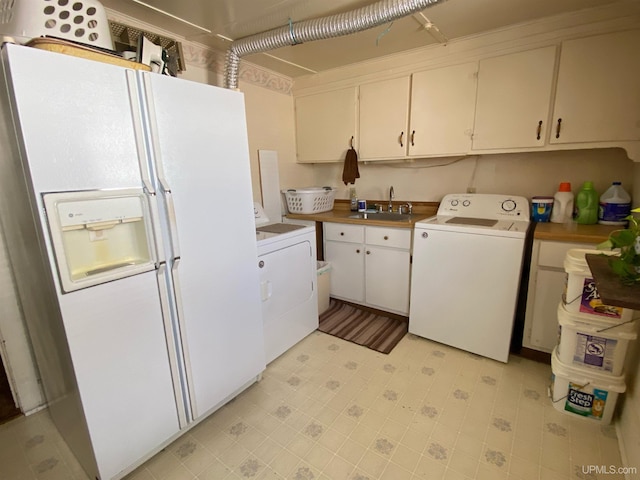 laundry area featuring light tile floors, cabinets, washer and clothes dryer, and sink