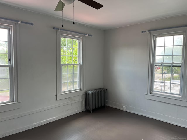 unfurnished room with ceiling fan, dark hardwood / wood-style floors, radiator, and plenty of natural light