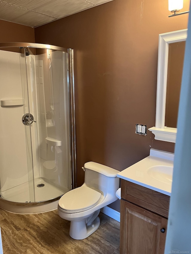 bathroom with a shower with shower door, vanity, hardwood / wood-style flooring, and toilet