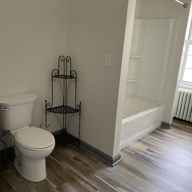 bathroom featuring toilet, radiator, shower / bath combination, and hardwood / wood-style floors