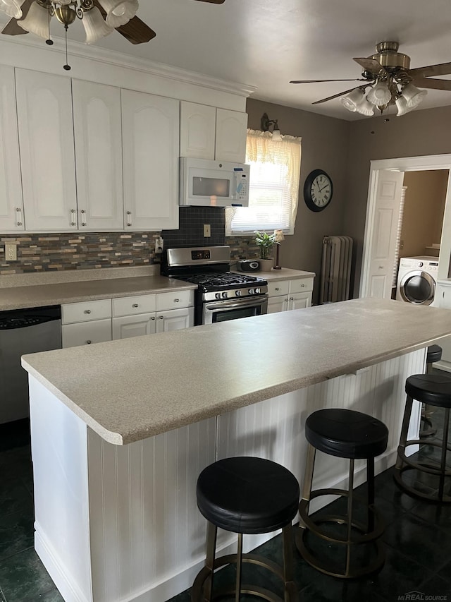 kitchen with white cabinets, ceiling fan, stainless steel appliances, and tasteful backsplash