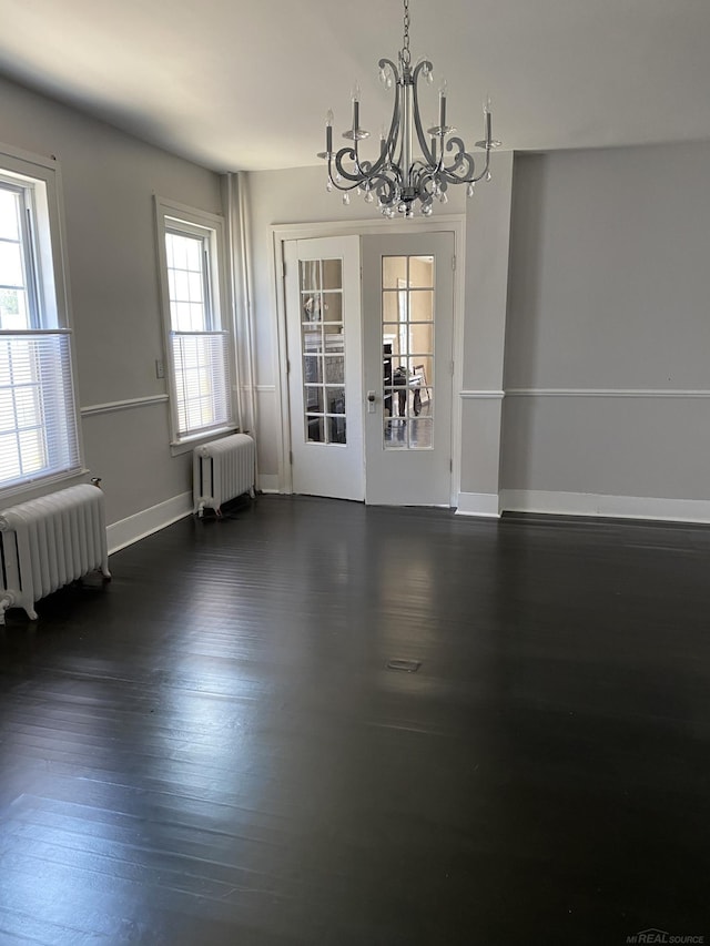 unfurnished dining area featuring dark hardwood / wood-style floors, radiator, and an inviting chandelier