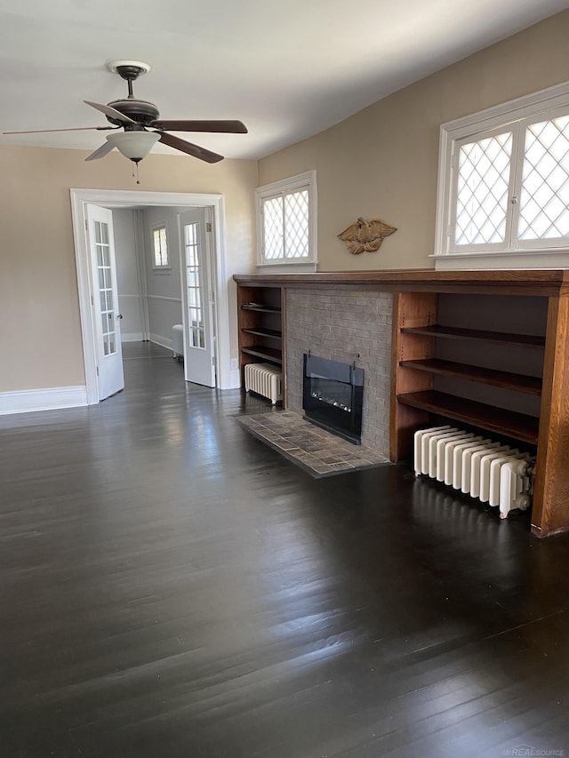 unfurnished living room featuring french doors, dark hardwood / wood-style floors, ceiling fan, and radiator