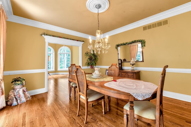 dining space featuring an inviting chandelier, light wood-type flooring, and crown molding