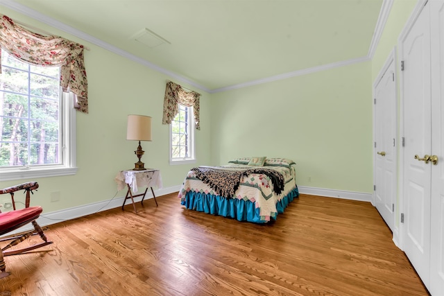 bedroom with crown molding, wood-type flooring, and multiple windows