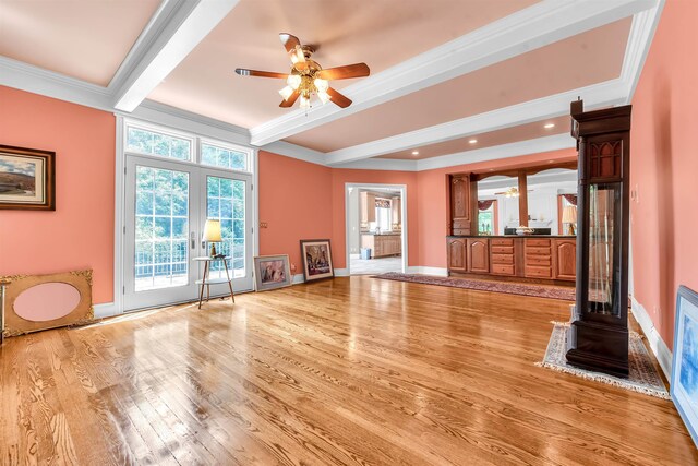 unfurnished living room with ceiling fan, beam ceiling, light wood-type flooring, and ornamental molding