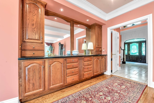 kitchen with beam ceiling, crown molding, dark stone countertops, and light tile flooring