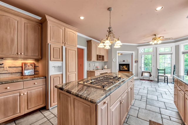 kitchen featuring tasteful backsplash, stainless steel gas stovetop, a kitchen island, light tile floors, and hanging light fixtures