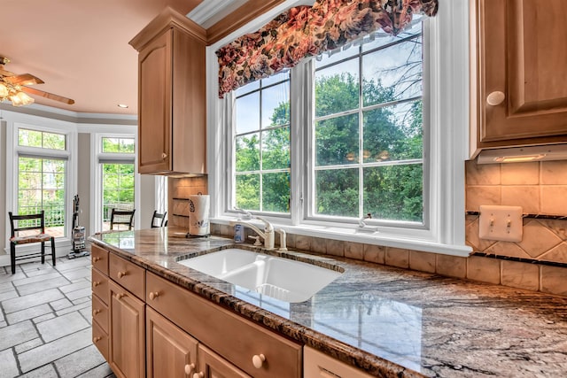 kitchen featuring stone countertops, backsplash, sink, ceiling fan, and light tile floors