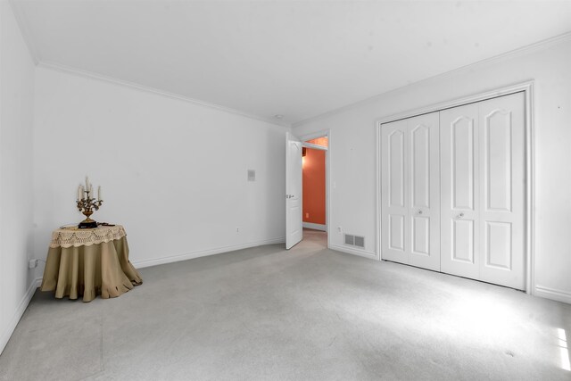 unfurnished bedroom with crown molding, carpet flooring, and a closet