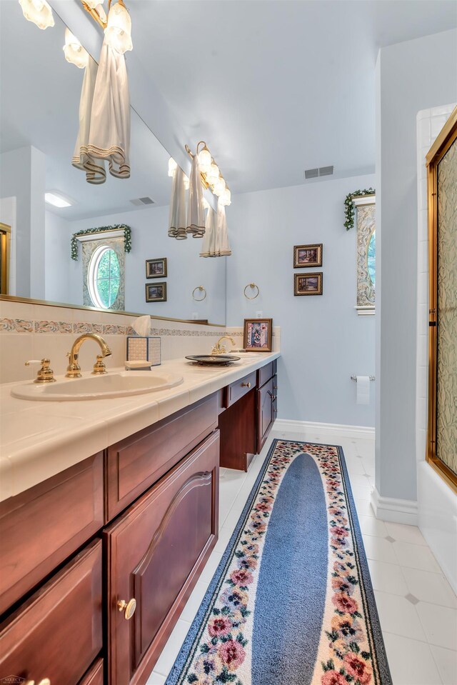 bathroom featuring enclosed tub / shower combo, tile floors, oversized vanity, and dual sinks