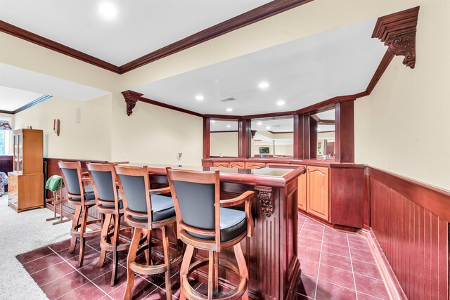 interior space with a center island, carpet floors, crown molding, and a breakfast bar area