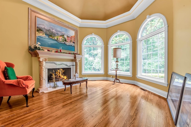 sitting room featuring ornamental molding, plenty of natural light, a high end fireplace, and hardwood / wood-style floors