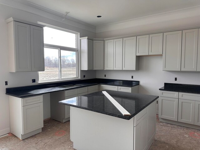 kitchen with a center island, light tile floors, white cabinets, sink, and dark stone countertops