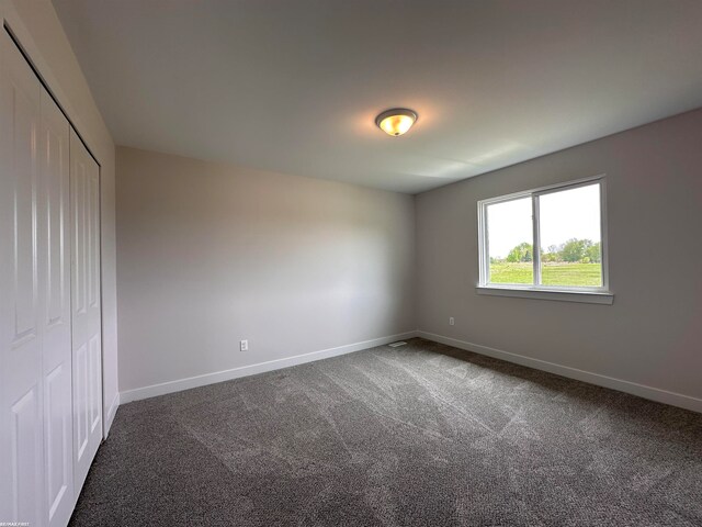 unfurnished bedroom featuring a closet and dark carpet