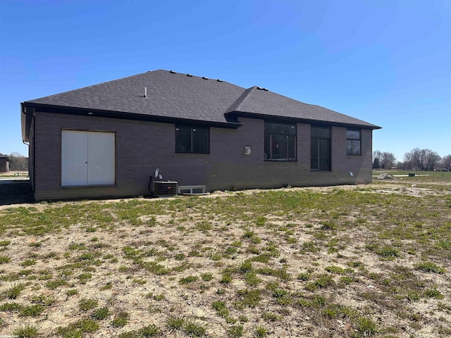 back of property featuring a lawn and central air condition unit