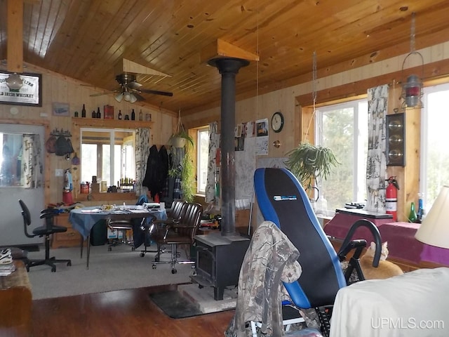 dining area featuring plenty of natural light, vaulted ceiling, and a wood stove