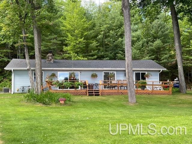 rear view of house featuring cooling unit, a wooden deck, and a yard