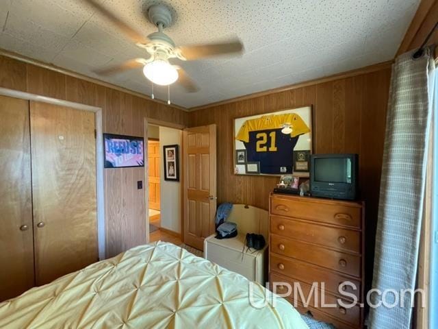 bedroom featuring wood walls, a closet, and ceiling fan