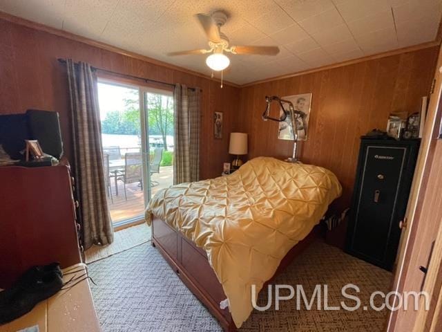 bedroom featuring access to exterior, ceiling fan, and wooden walls