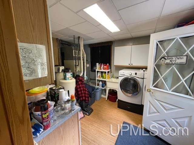 washroom featuring washer / clothes dryer, cabinets, and wood-type flooring