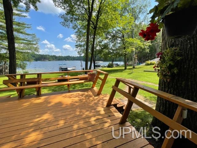 wooden terrace with a water view and a yard