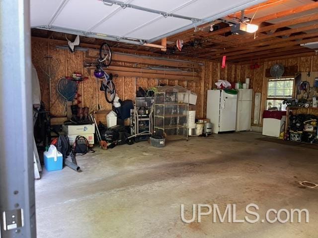 garage featuring white refrigerator and a garage door opener