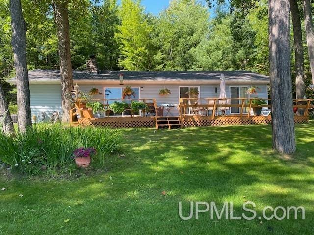 rear view of house with a wooden deck and a lawn