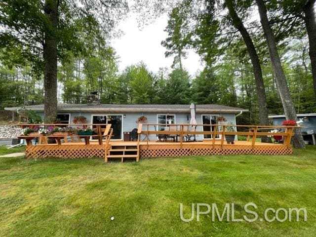 rear view of property featuring a deck and a lawn