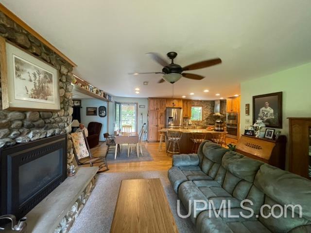 living room featuring a fireplace, light hardwood / wood-style flooring, and ceiling fan