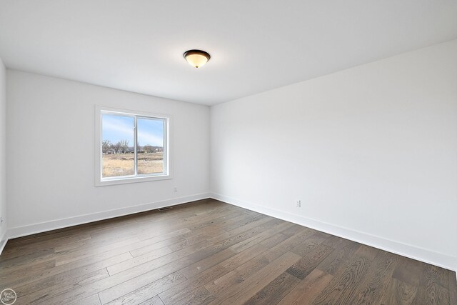 spare room featuring dark wood-style floors and baseboards