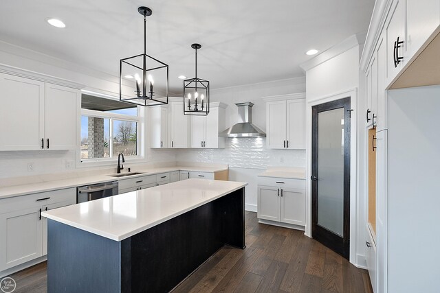 kitchen featuring backsplash, stainless steel dishwasher, dark wood-type flooring, a sink, and wall chimney range hood