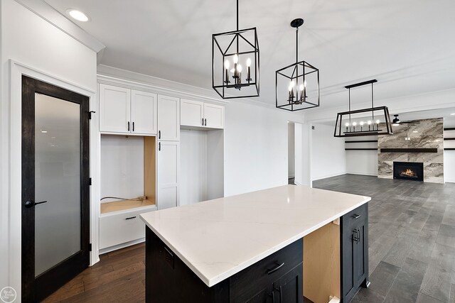 kitchen with a fireplace, white cabinetry, dark wood-type flooring, and a center island