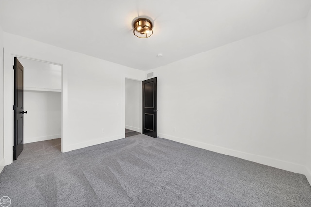 unfurnished bedroom with dark colored carpet and a closet