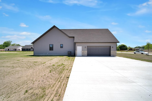 view of front of property featuring cooling unit, a garage, and a front yard