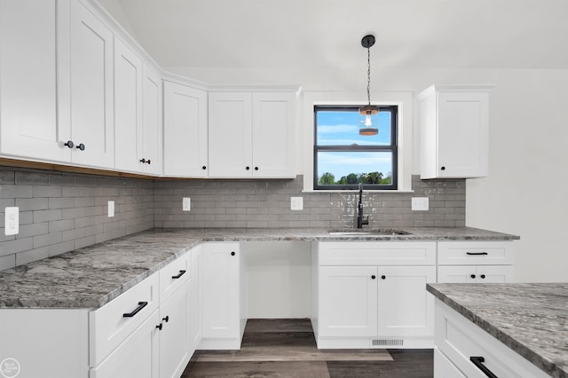 kitchen with white cabinets, backsplash, light stone countertops, and sink