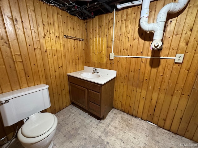 bathroom featuring tile flooring, wooden walls, vanity, and toilet