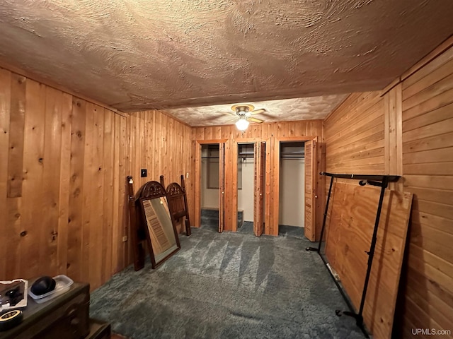 interior space featuring ceiling fan and dark carpet