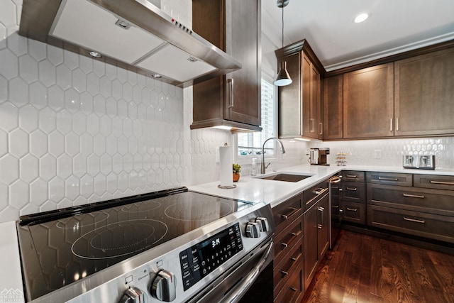 kitchen with dark wood-type flooring, wall chimney exhaust hood, sink, stainless steel electric range, and pendant lighting