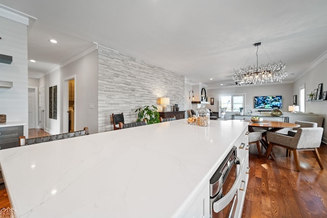 kitchen with pendant lighting, crown molding, dark wood-type flooring, a center island, and light stone countertops