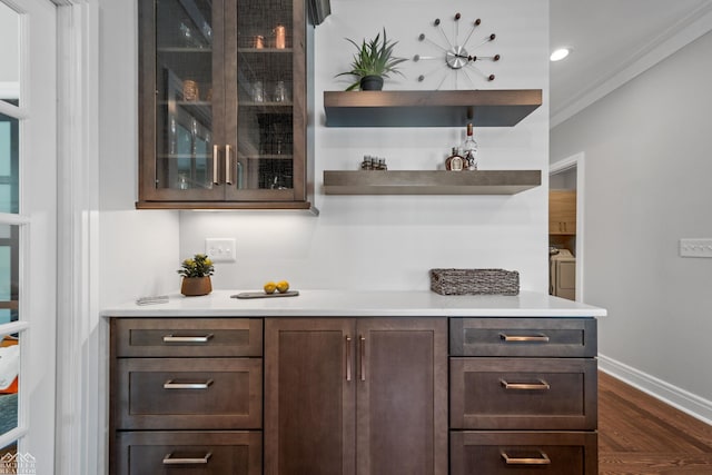 bar featuring dark hardwood / wood-style flooring, crown molding, dark brown cabinets, and washer and dryer