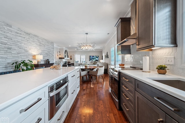 kitchen with dark wood-type flooring, stainless steel range with electric stovetop, pendant lighting, decorative backsplash, and white cabinets