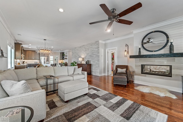 living room featuring ornamental molding, dark hardwood / wood-style floors, ceiling fan with notable chandelier, and a tile fireplace