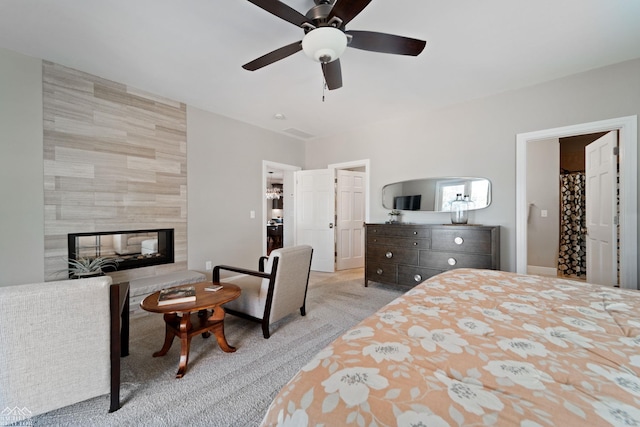 carpeted bedroom with ceiling fan and a fireplace