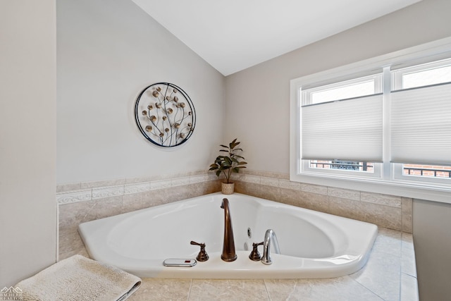 bathroom featuring lofted ceiling and tiled tub