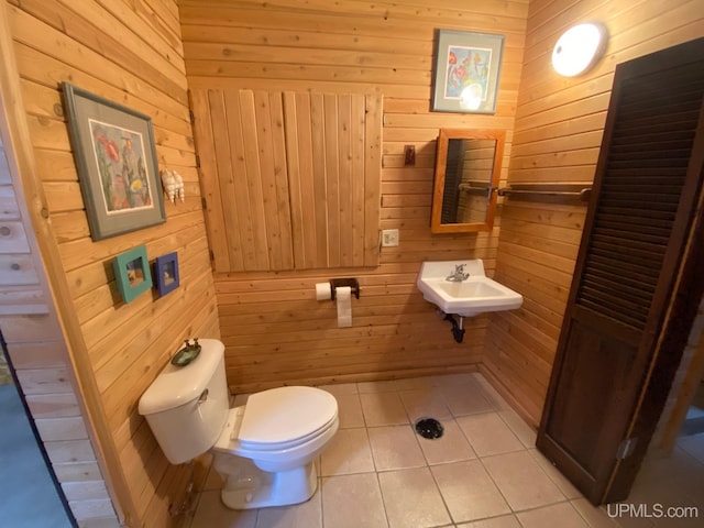 bathroom featuring tile patterned flooring, toilet, wood walls, and sink