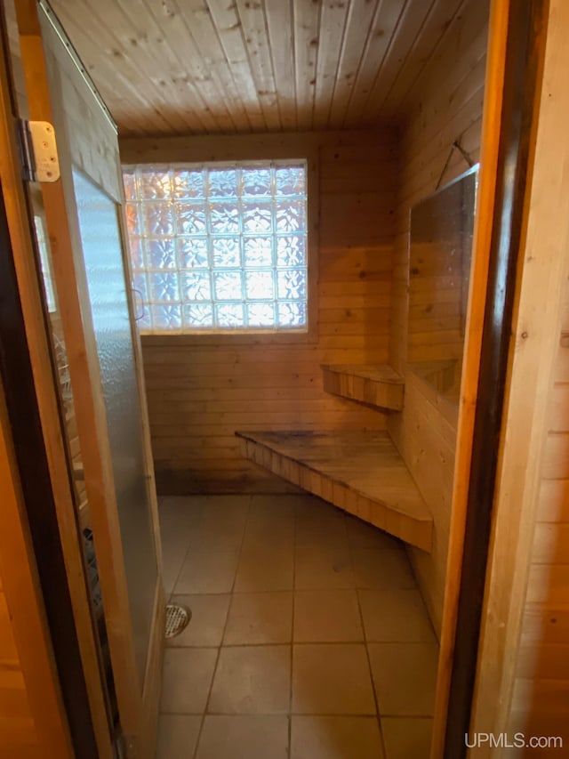 interior space featuring tile patterned floors, wooden walls, and wooden ceiling