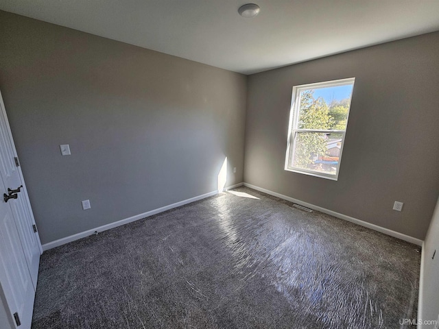 carpeted spare room featuring baseboards and visible vents